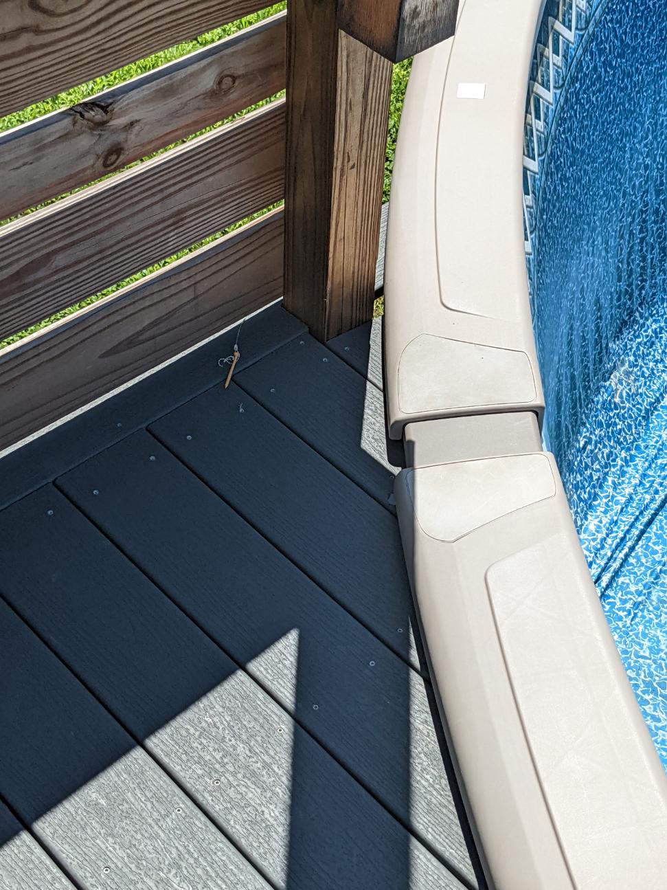 Top rails of an above ground pool very close to a wood deck