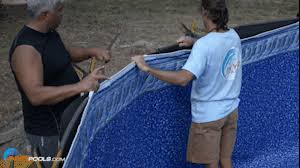 Two above ground pool installers setting a liner in place