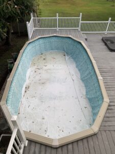 Oval above ground pool that is empty and surrounded by a wood deck