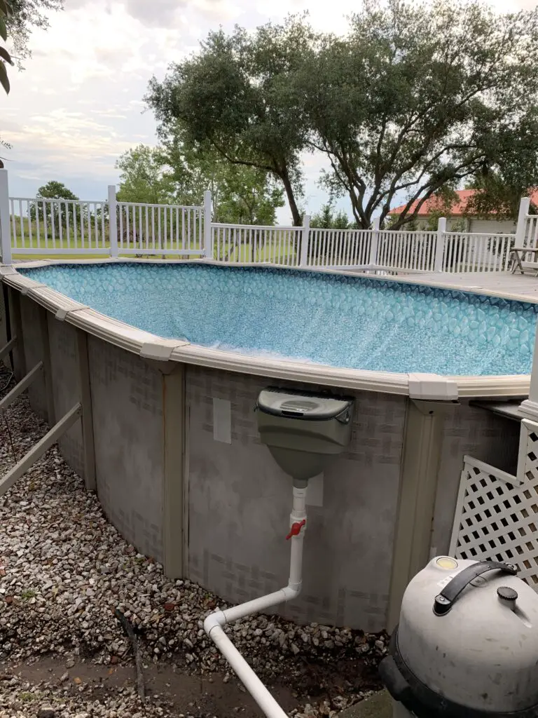 Oval above ground pool with the skimmer attached just outside the deck area