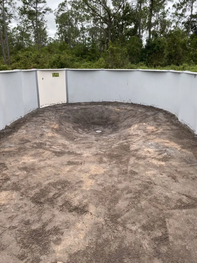 Deep end, main drain, and service panel in an oval above ground pool before the liner goes in