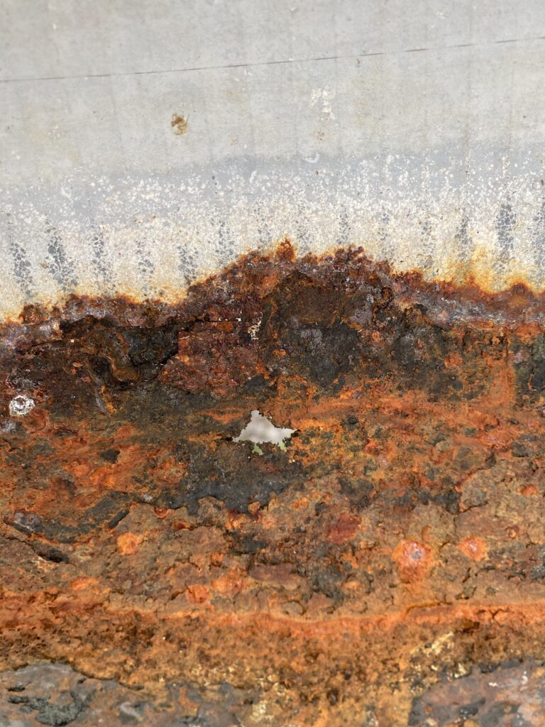 Rust caused a hole in the metal wall of an above ground pool due to an unfixed leak