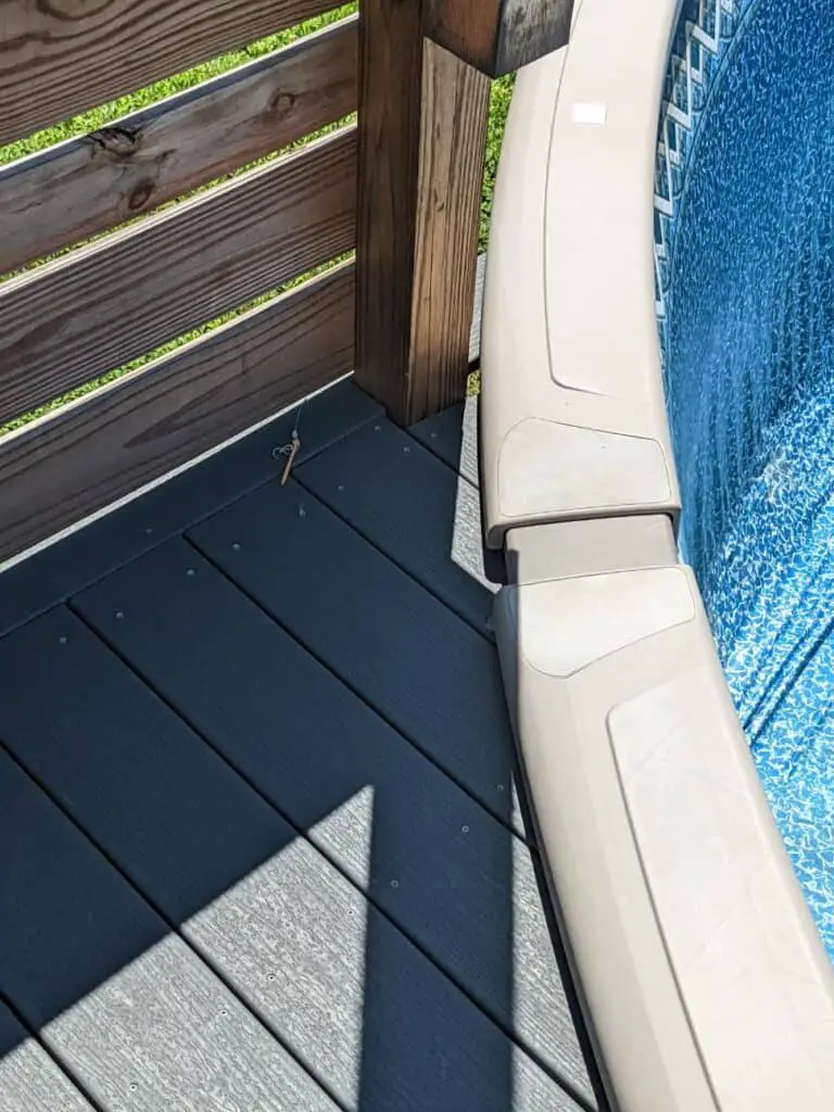 Wood deck is running under the top rails of an above ground pool