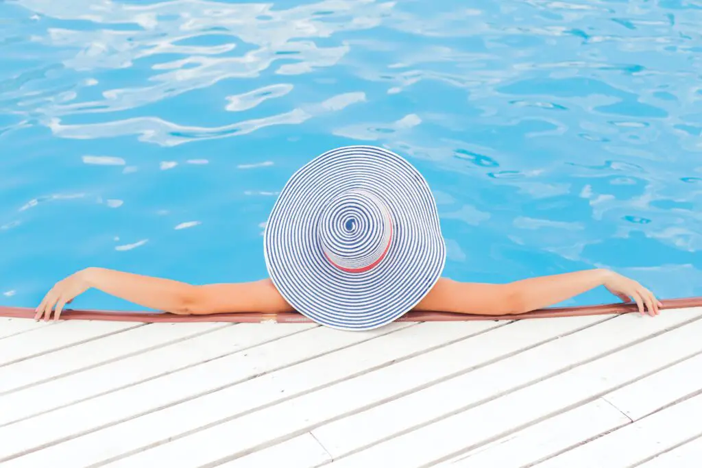 Girl in above ground pool wearing a hat