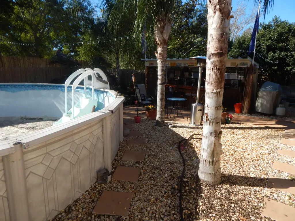 Two palm trees placed very close to an above ground swimming pool