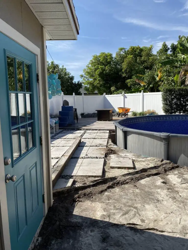 Round above ground swimming pool recessed halfway in the ground next to an existing ground level deck