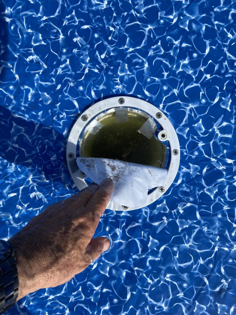 Removing the piece of liner cut out for a main drain in a vinyl pool